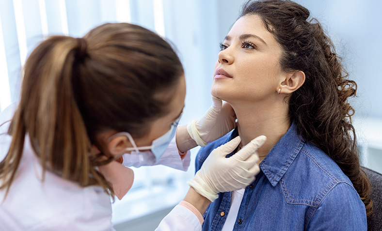 medico visita una giovane donna osservandone da vicino il collo